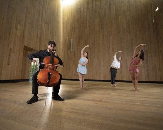 A person plays a cello while three people dance ballet behind them in an acoustically-designed environment of Berwick Hall