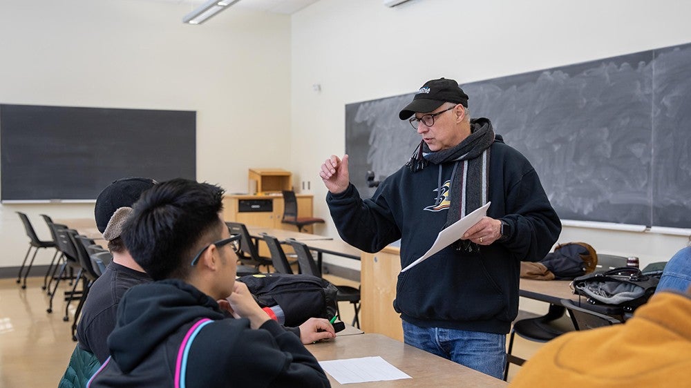 Dave Corranda speaking with two students in a classroom